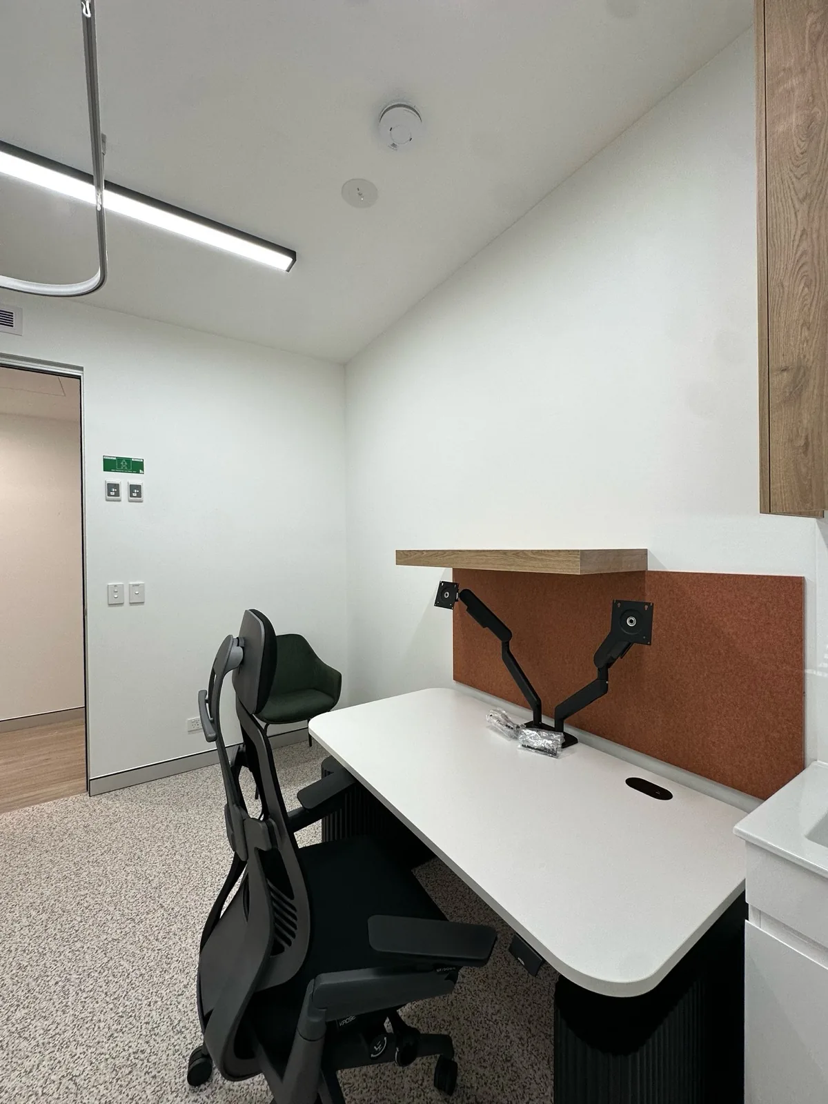 Medical consulting room with a sit-stand desk and dual monitor arms