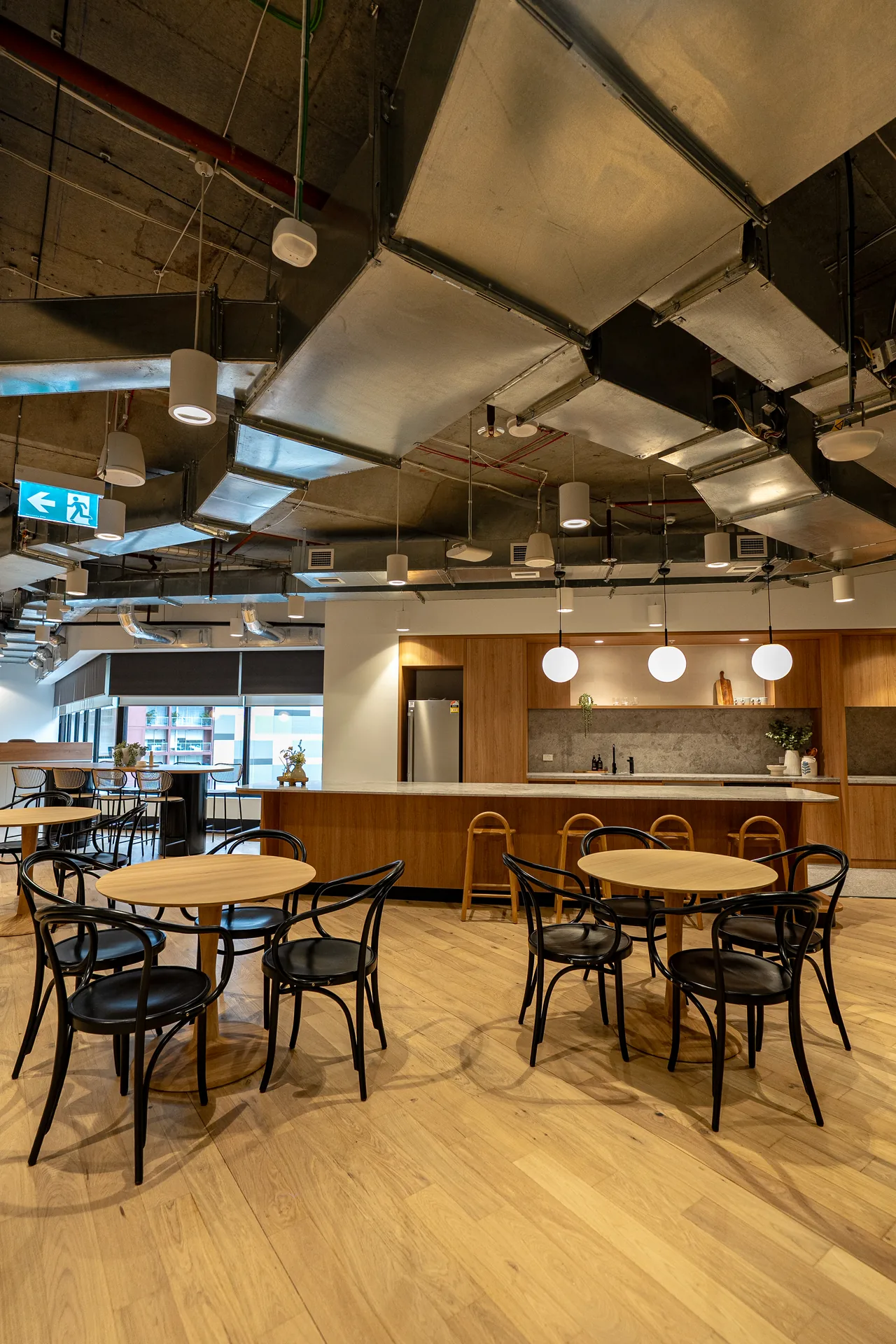 Café-style breakout area with round tables and bentwood chairs in a commercial office