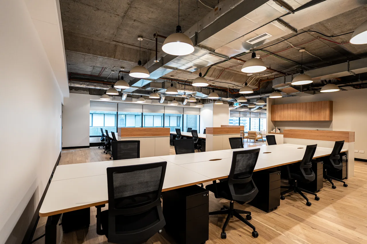 Rows of white-top workstations with black mesh chairs in an open-plan office